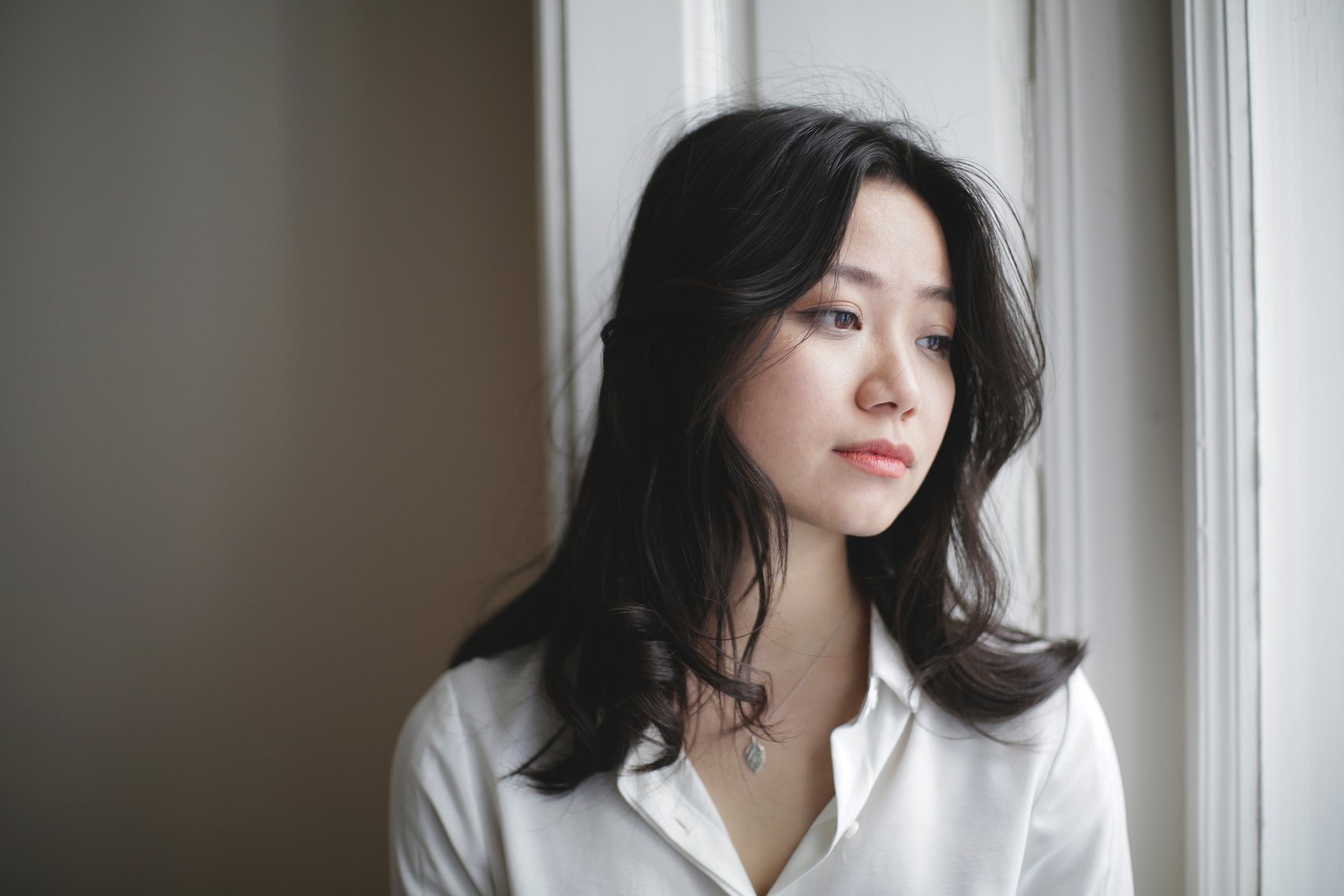 Dreamy Asian woman looking out window